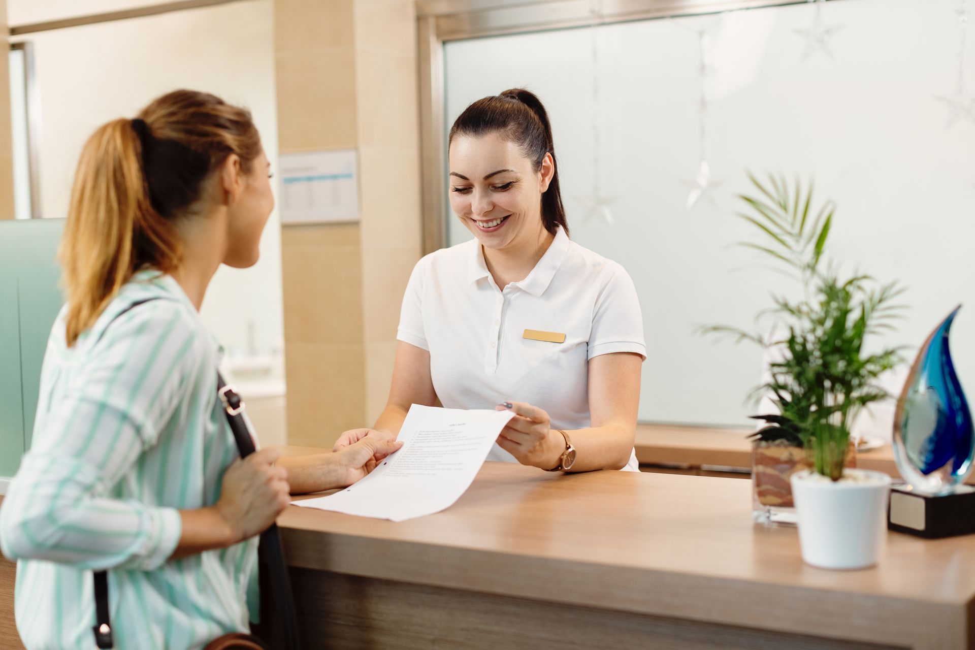 a woman is talking to a nurse at a reception desk in a hospital .