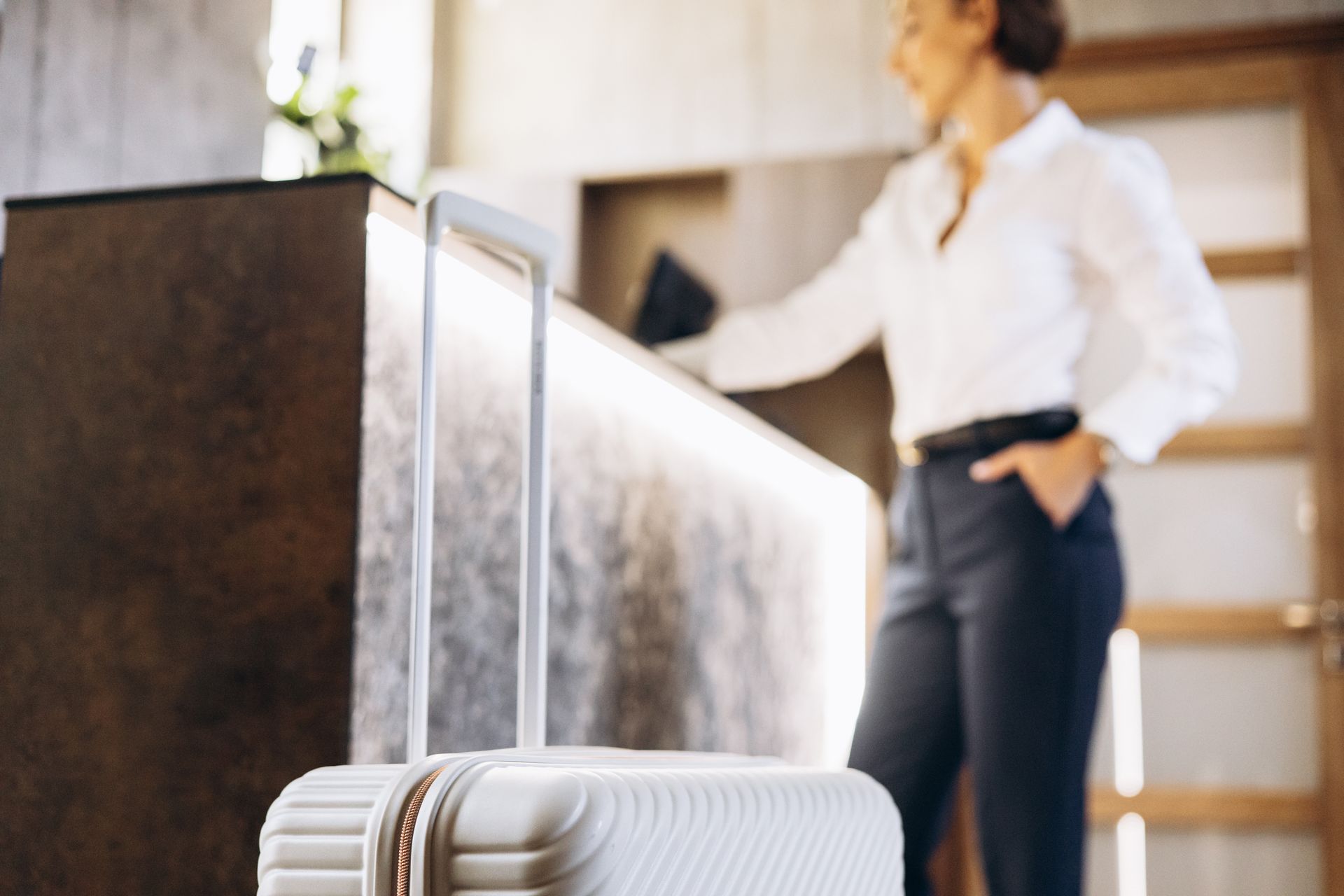 a woman is standing in a hotel lobby with a suitcase .