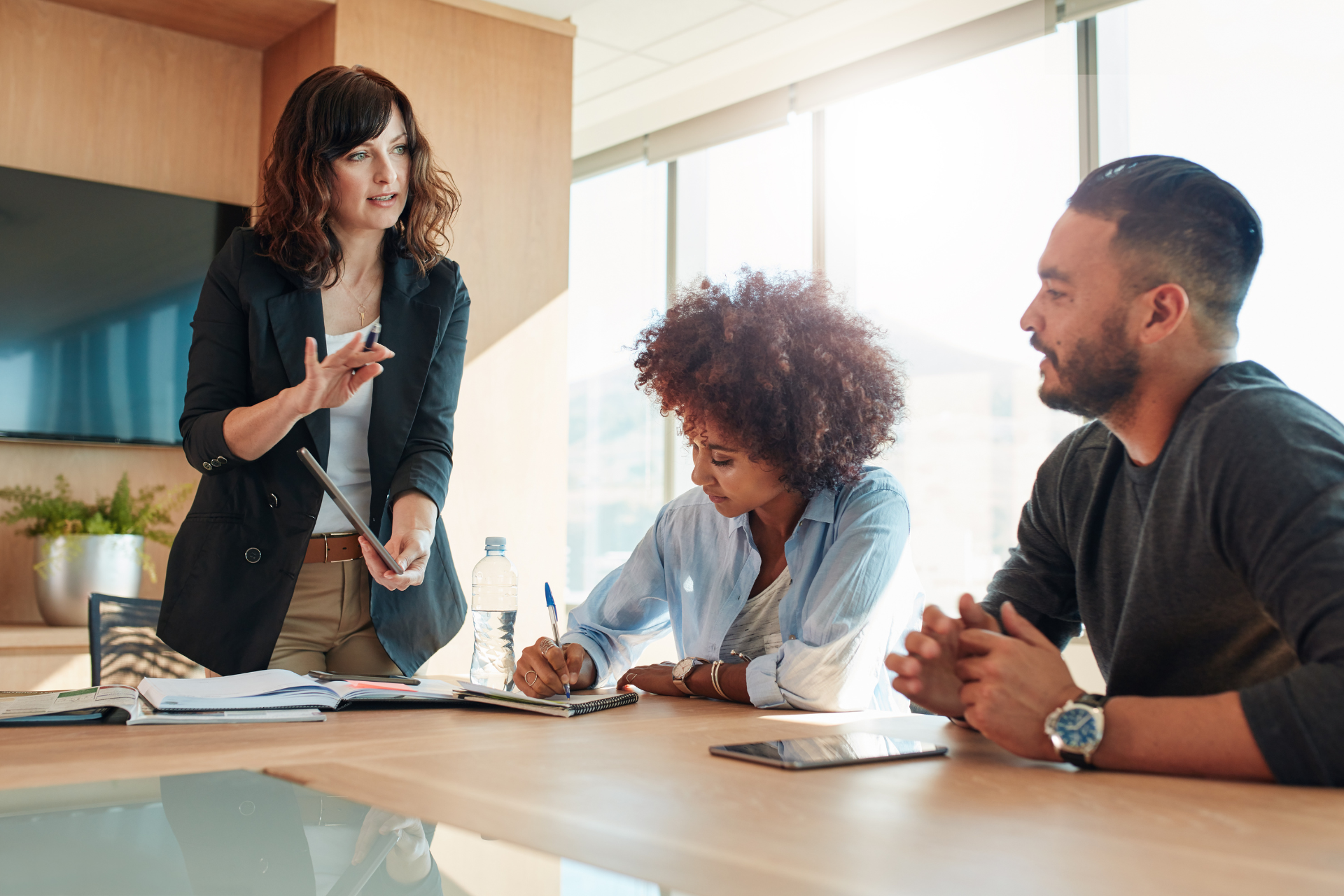 a group of people are sitting around a table having a meeting .