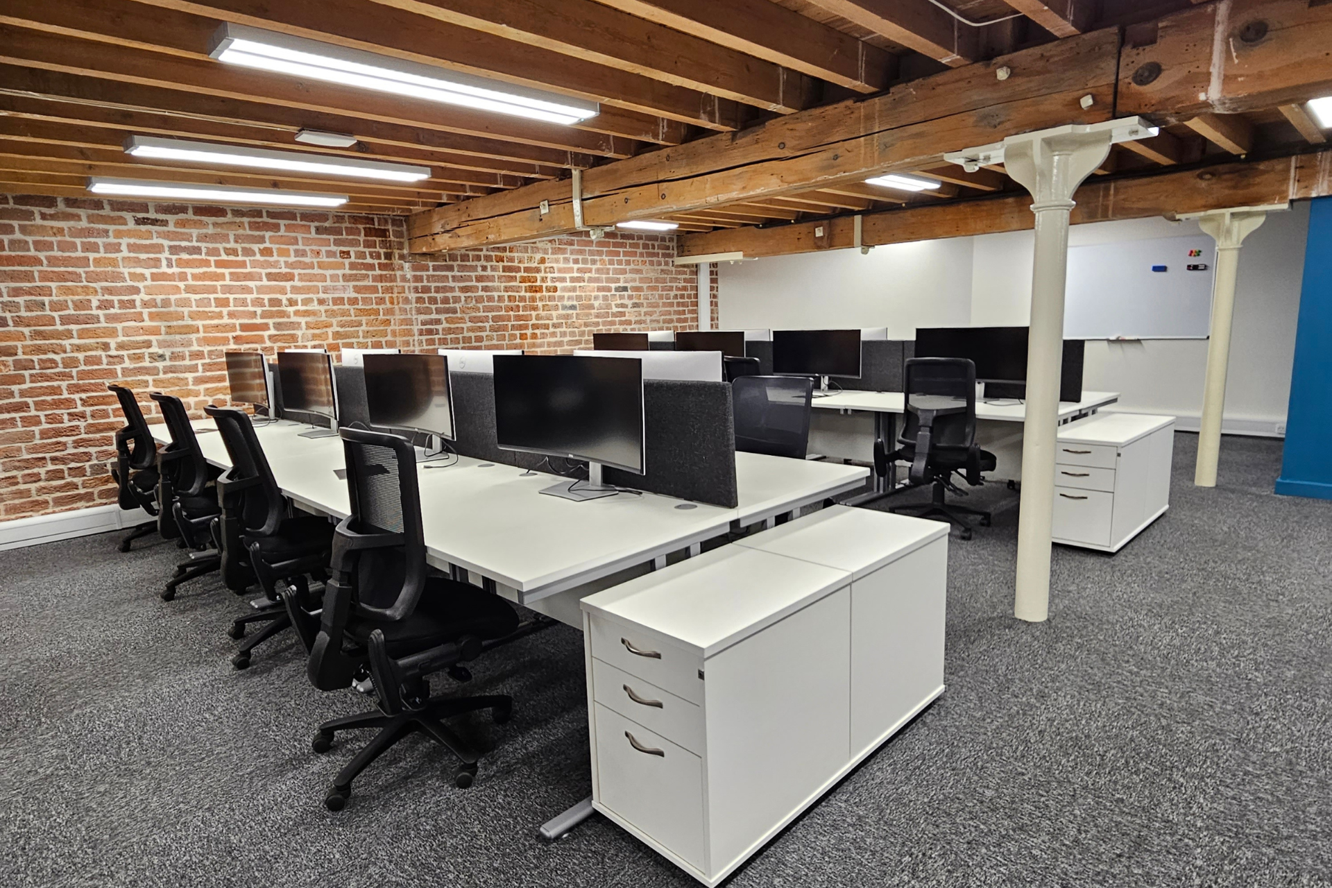 a room with a lot of desks and chairs and a brick wall .