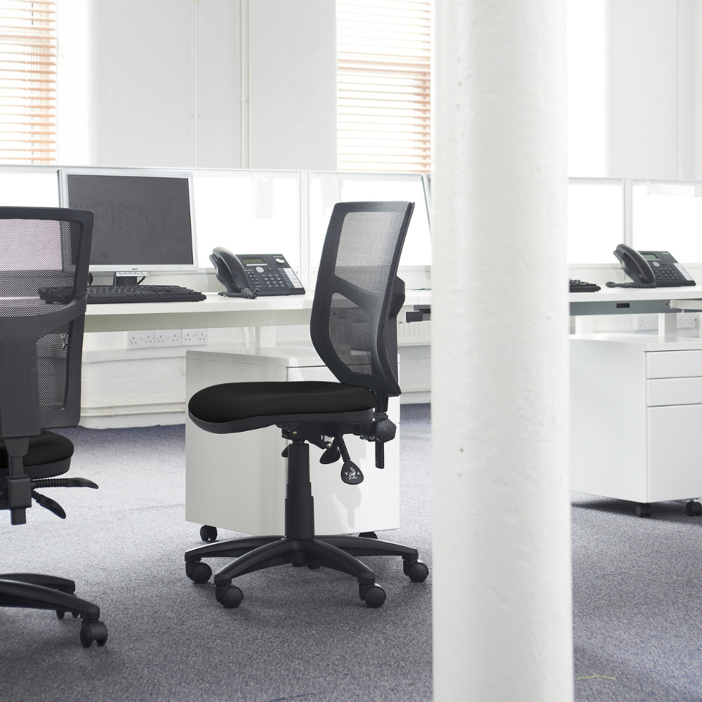 a black office chair sits in front of a computer desk