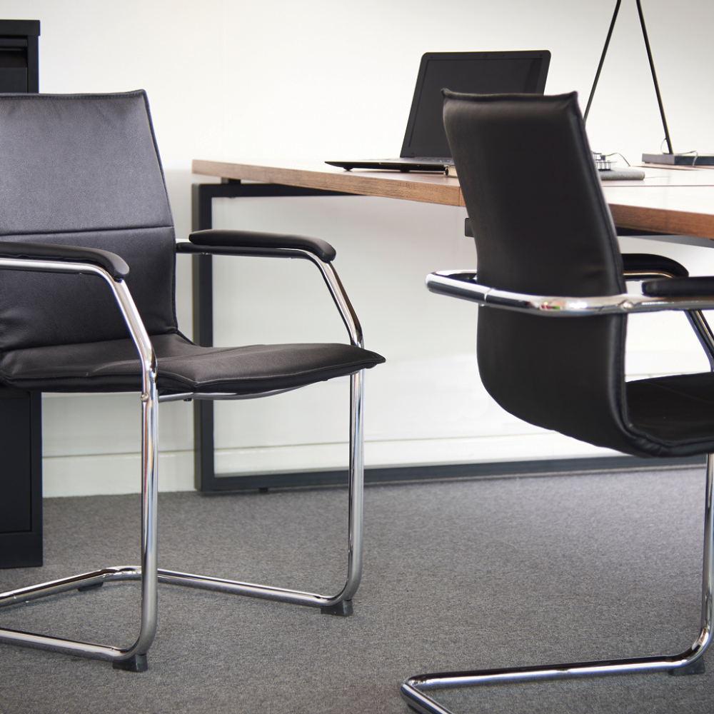 two black chairs sit in front of a desk with a laptop on it