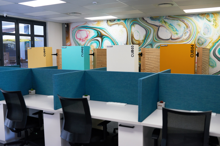 a row of cubicles in an office with a mural on the wall .