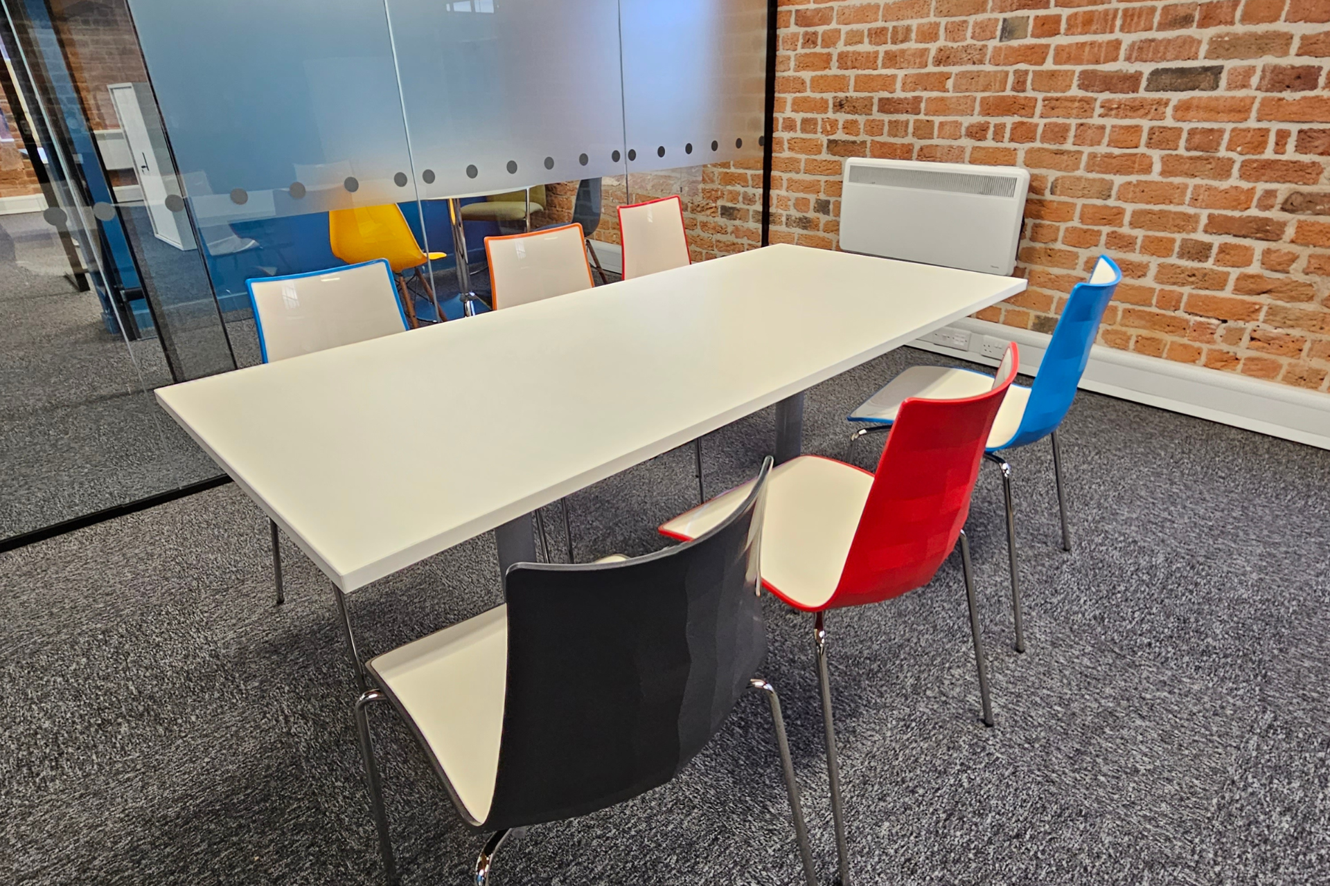 a conference room with a long table and chairs in front of a brick wall .