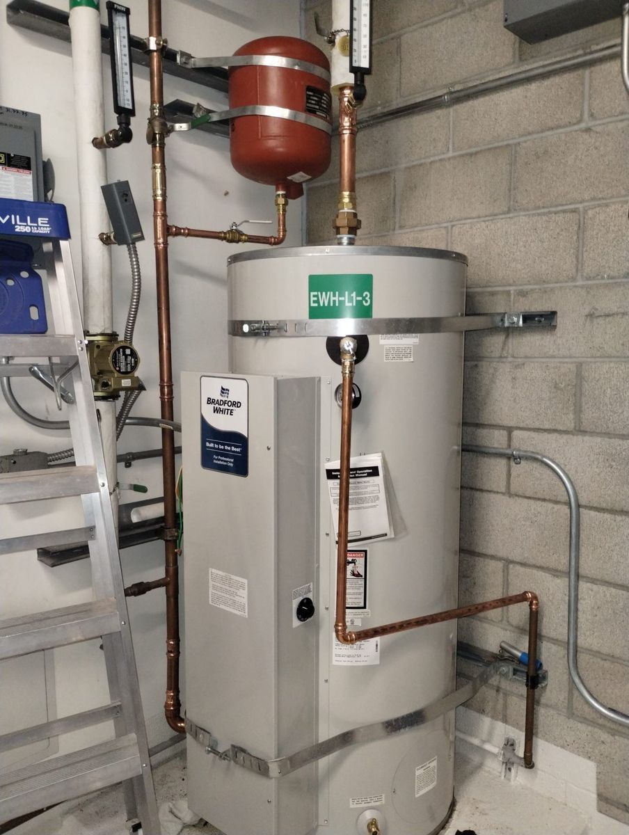 Water heater with copper pipes in a utility room.