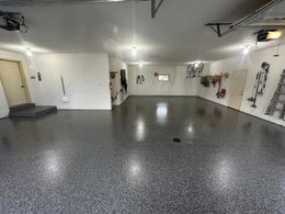A large empty garage with a gray floor and white walls.