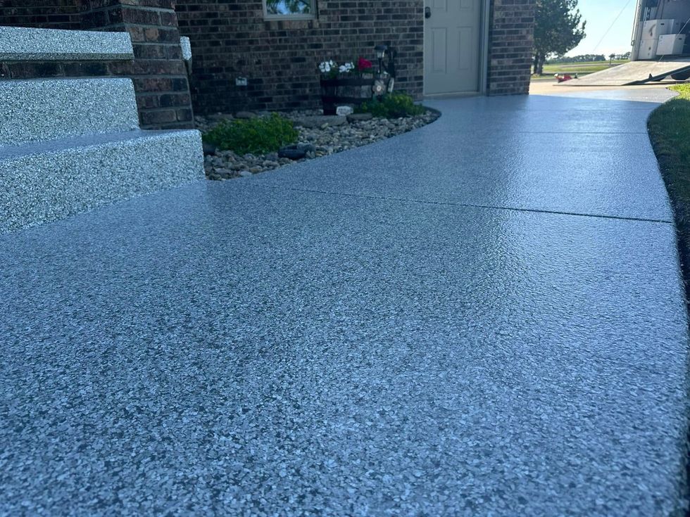 A gray concrete walkway leading to a brick house.