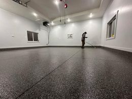 A man is cleaning the floor of a garage with a mop.