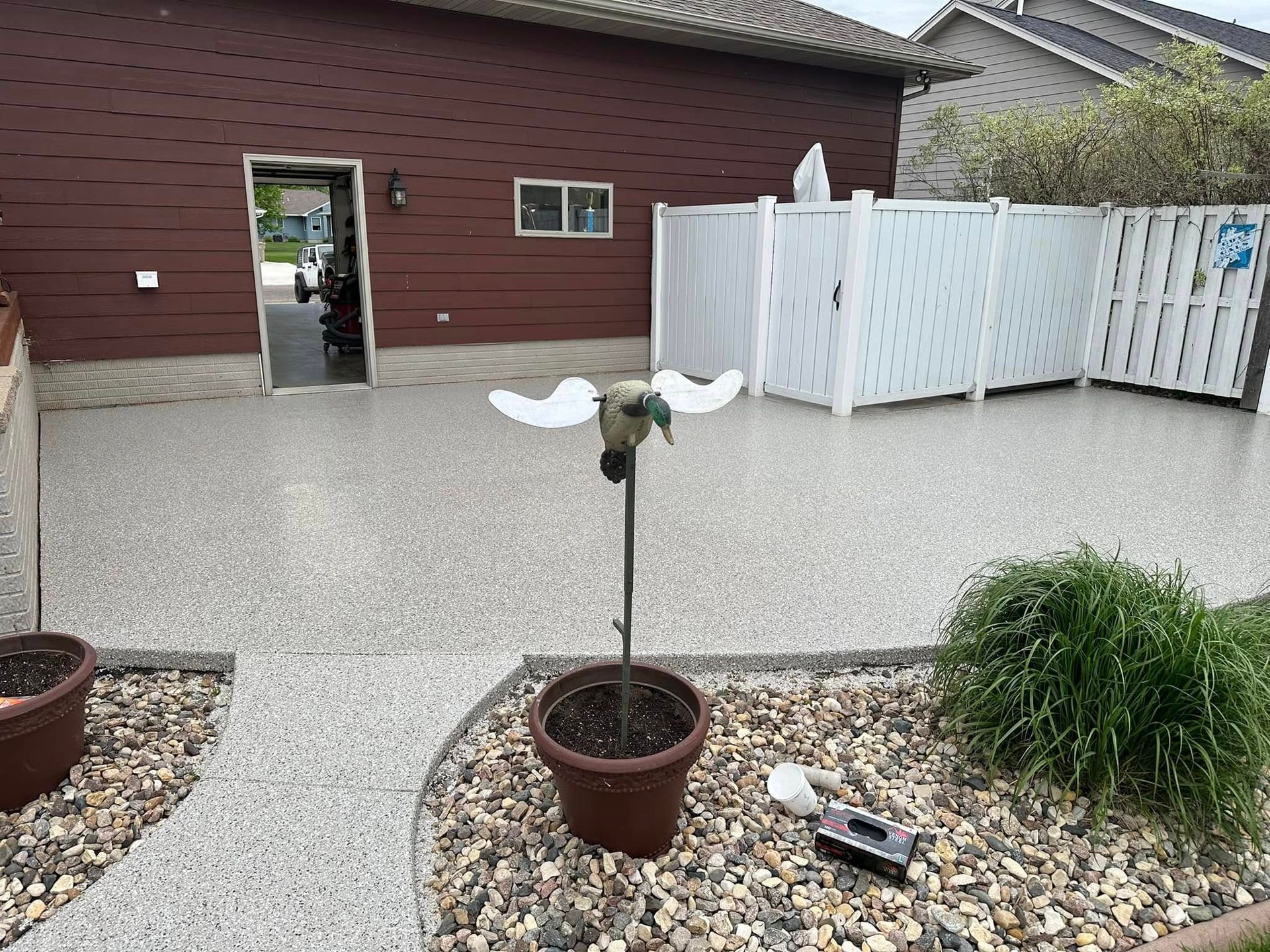 A bird statue is sitting in a pot in front of a house.