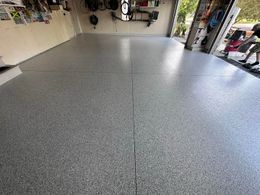 A garage with a gray floor and a white wall.