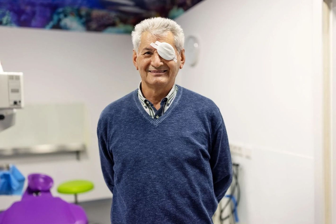 Uomo sorridente con una benda sull'occhio in un ambiente medico.