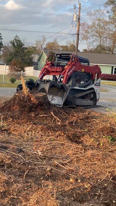 A bulldozer is moving a pile of dirt in a yard.