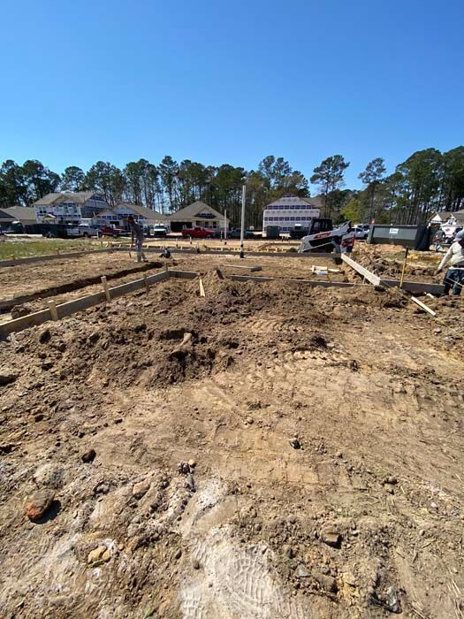 A construction site with a lot of dirt and trees in the background.
