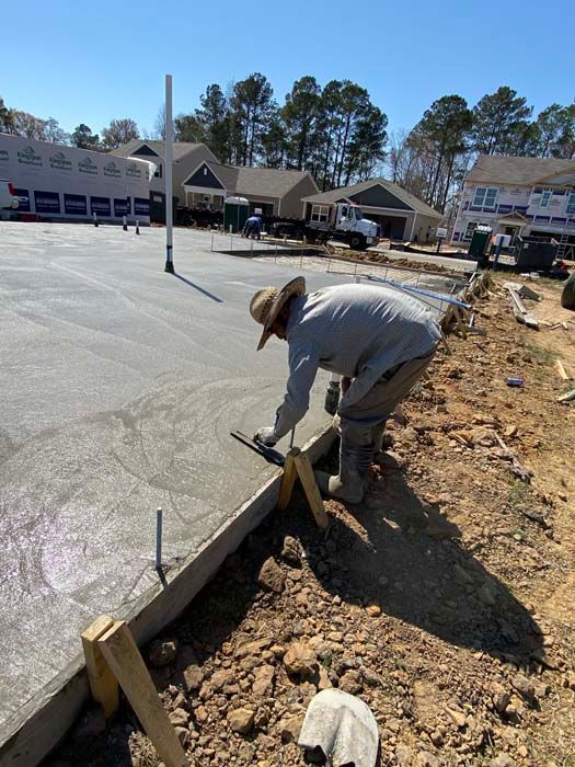 A man in a cowboy hat is working on a concrete driveway.