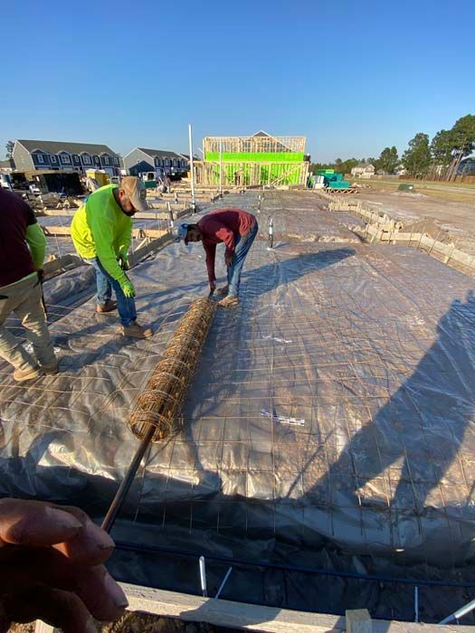 A group of construction workers are working on a concrete floor.