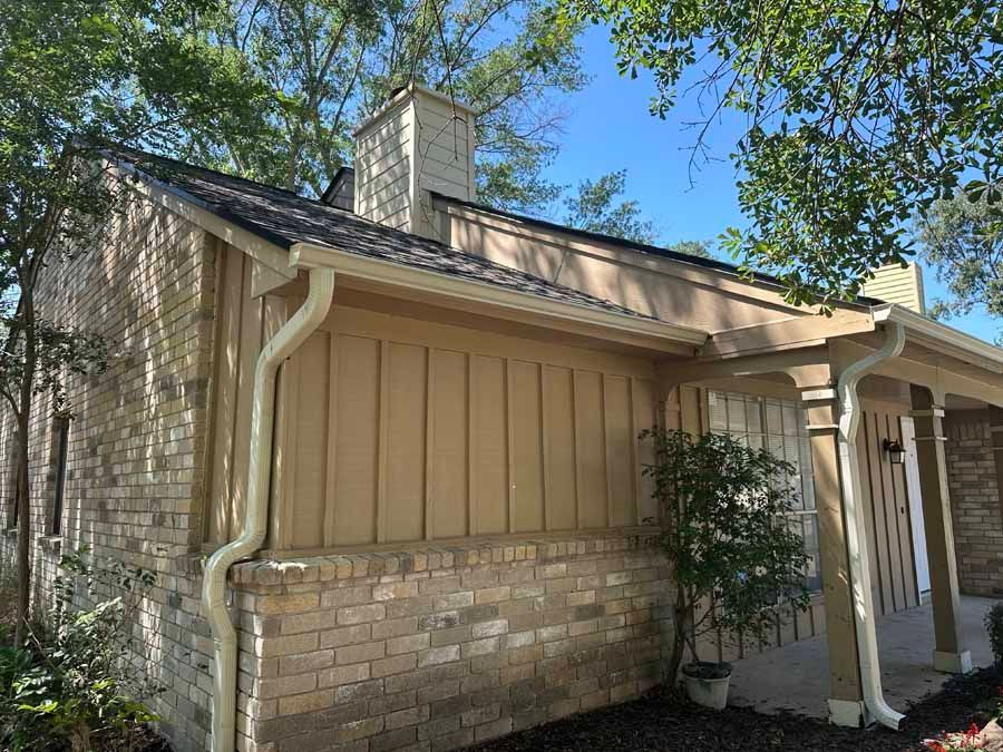 A brick house with a porch and a chimney on the roof.