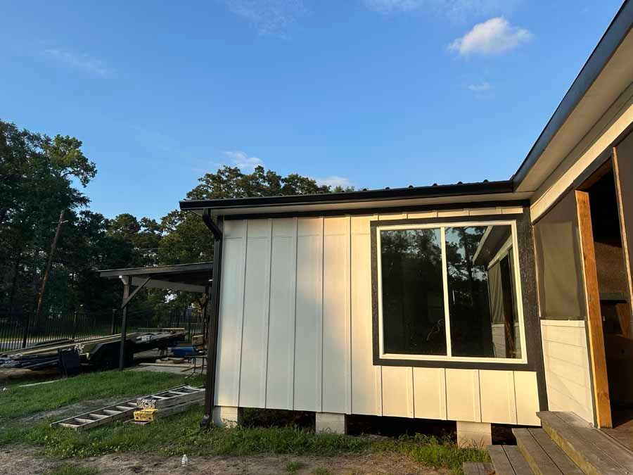 A small white house with a large window in the backyard.