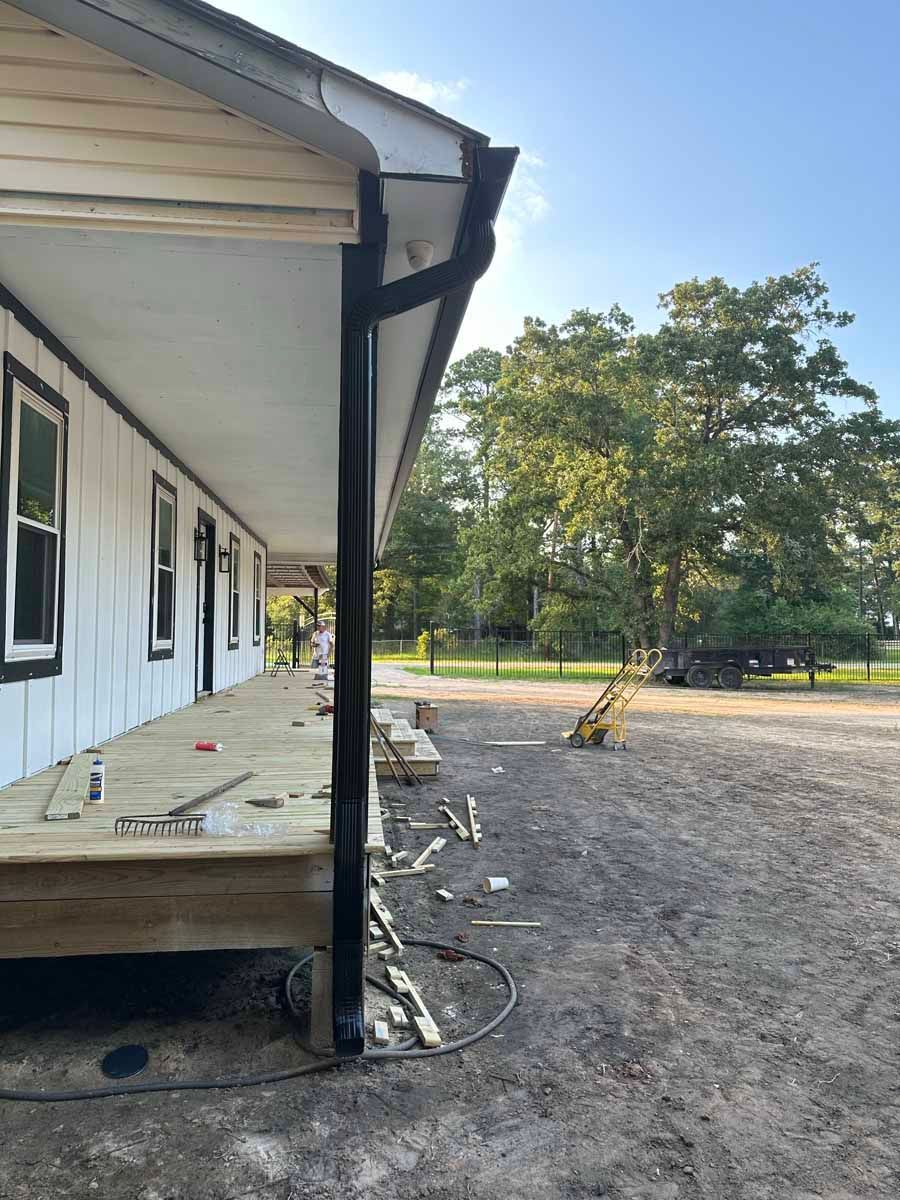 A house with a porch and a black gutter is being built.