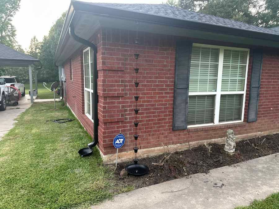 A red brick house with a gutter on the side of it.
