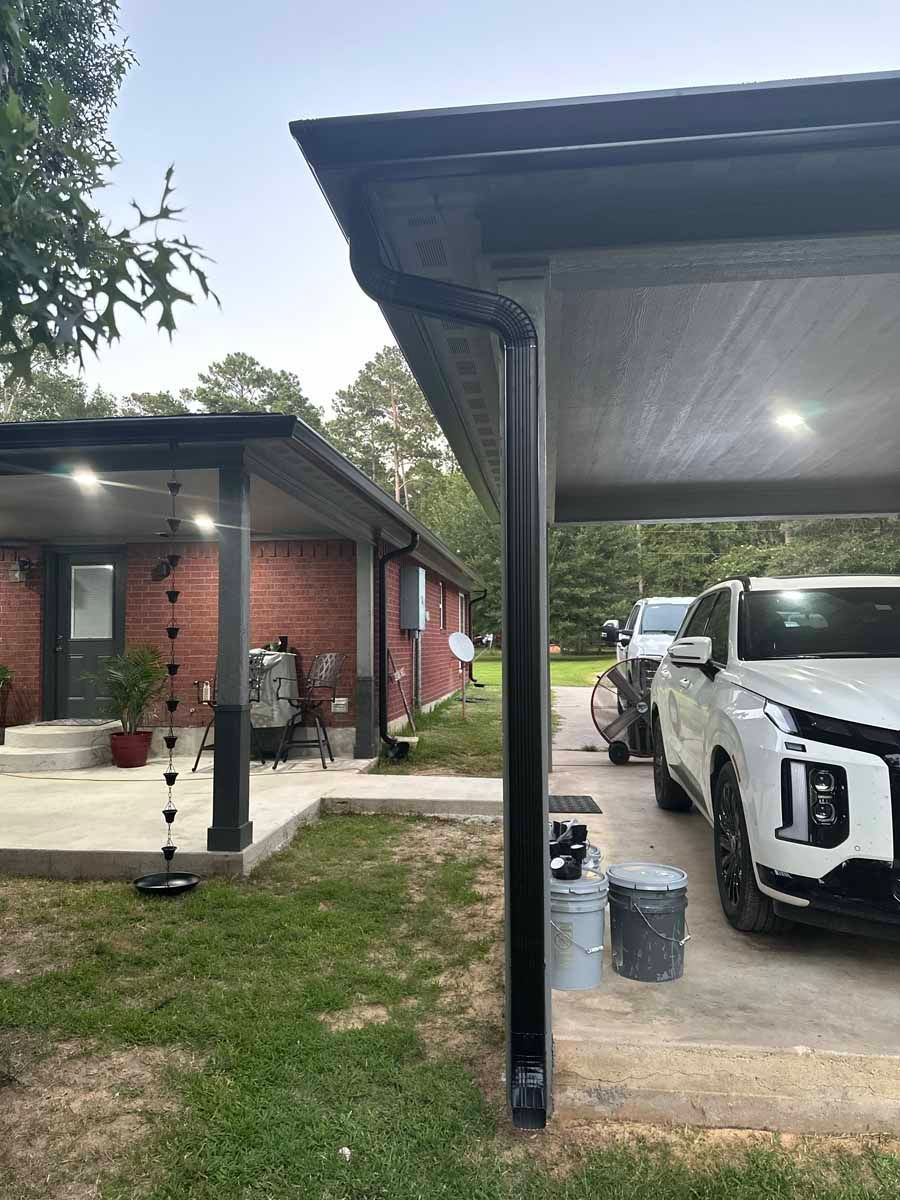 A white truck is parked under a carport in front of a house.