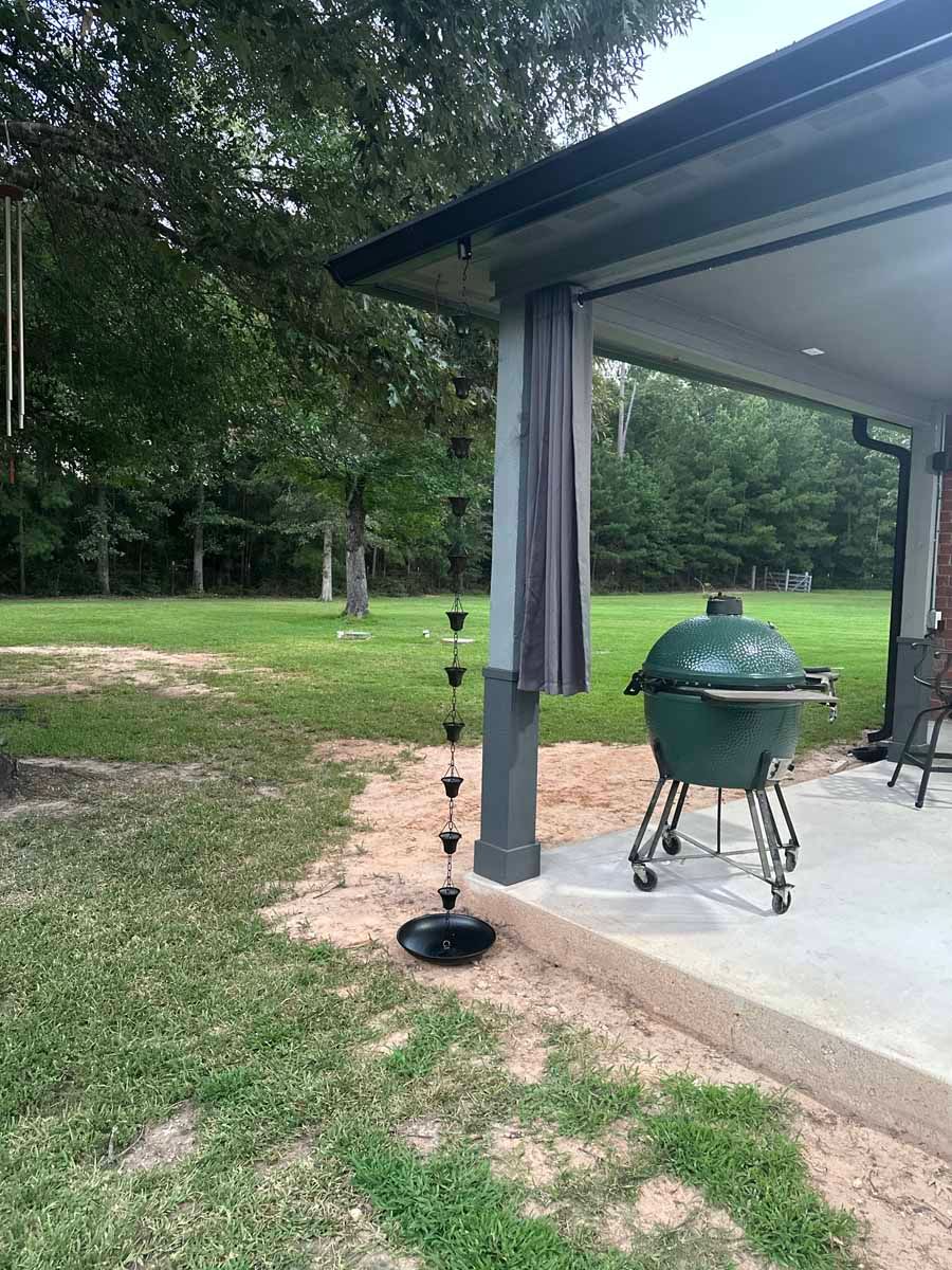 A green egg grill is sitting on a patio next to a house.