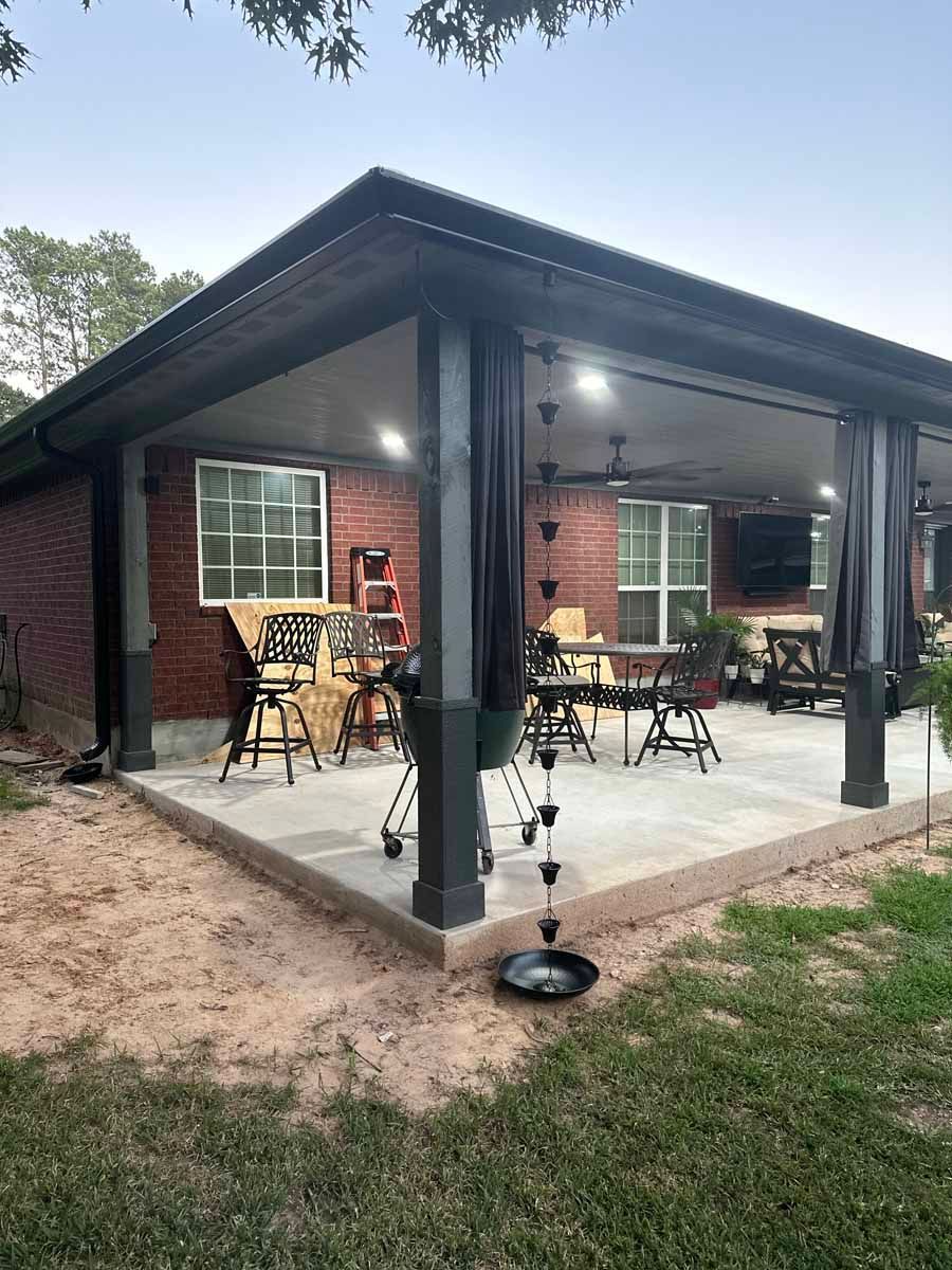 A brick house with a covered patio with tables and chairs.