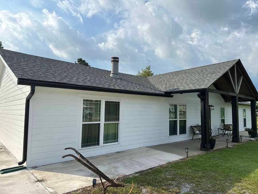 A white house with a black roof and a porch.
