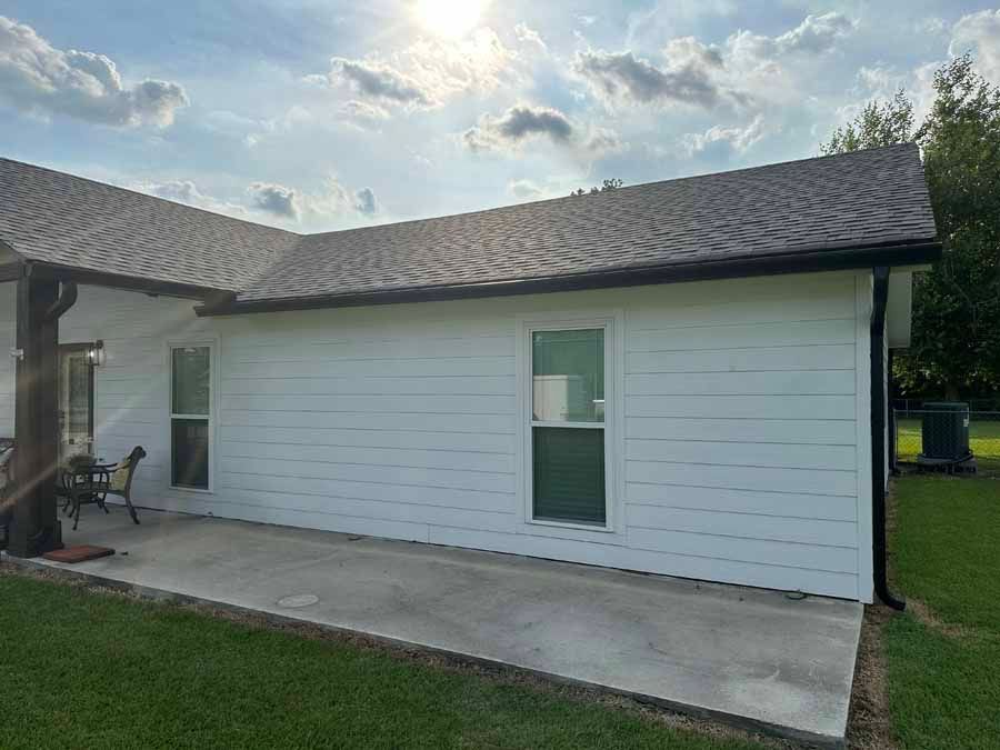 A white house with a gray roof and a patio in front of it.