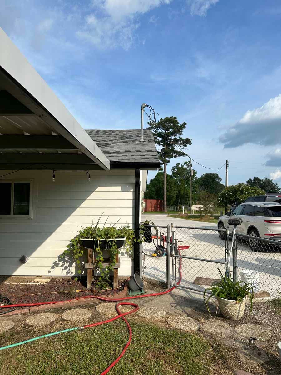 A white house with a chain link fence and a hose in front of it.