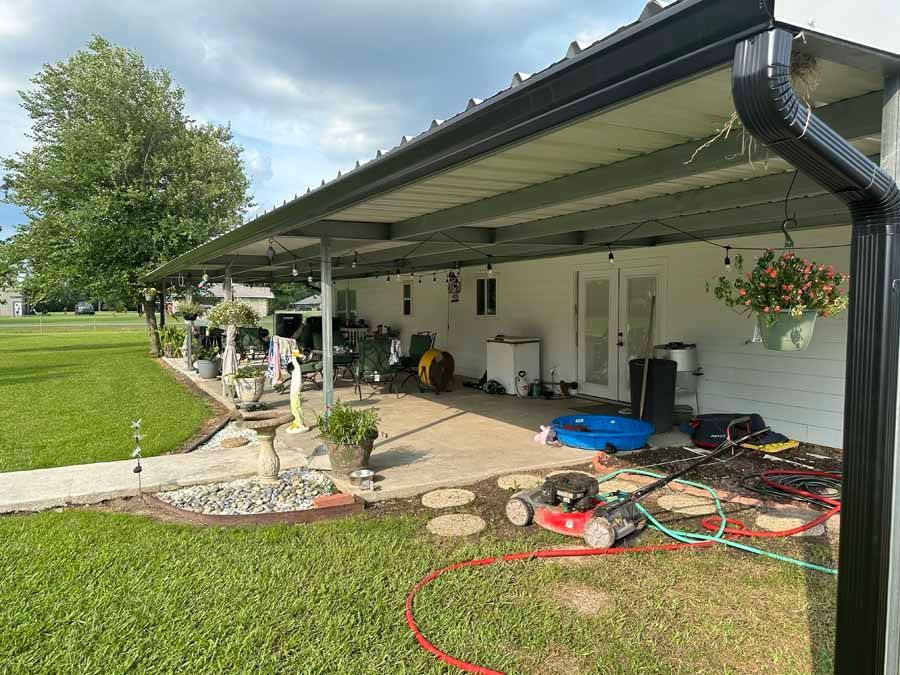 A white house with a covered porch and a lawn mower in front of it.