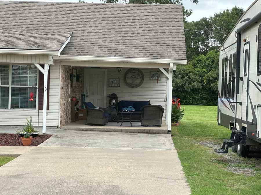 A house with a porch and a trailer parked in front of it.