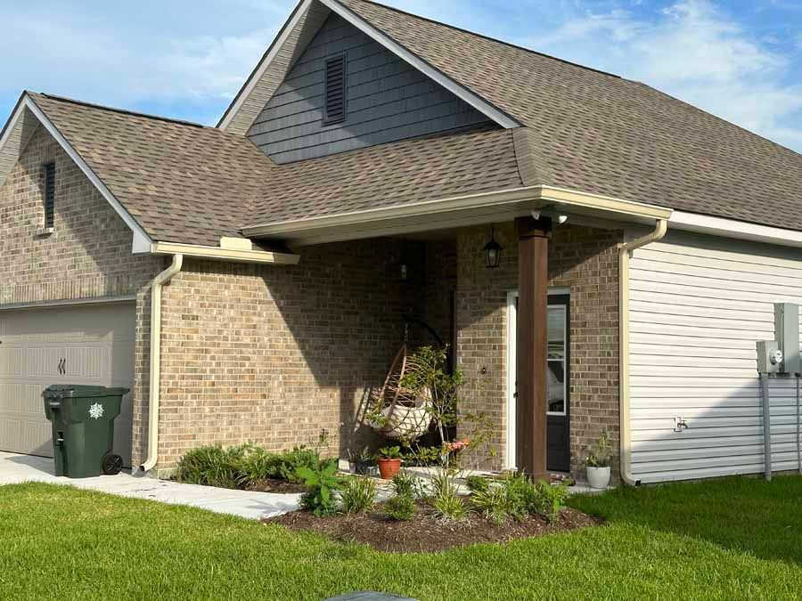 A brick house with a brown roof and white siding