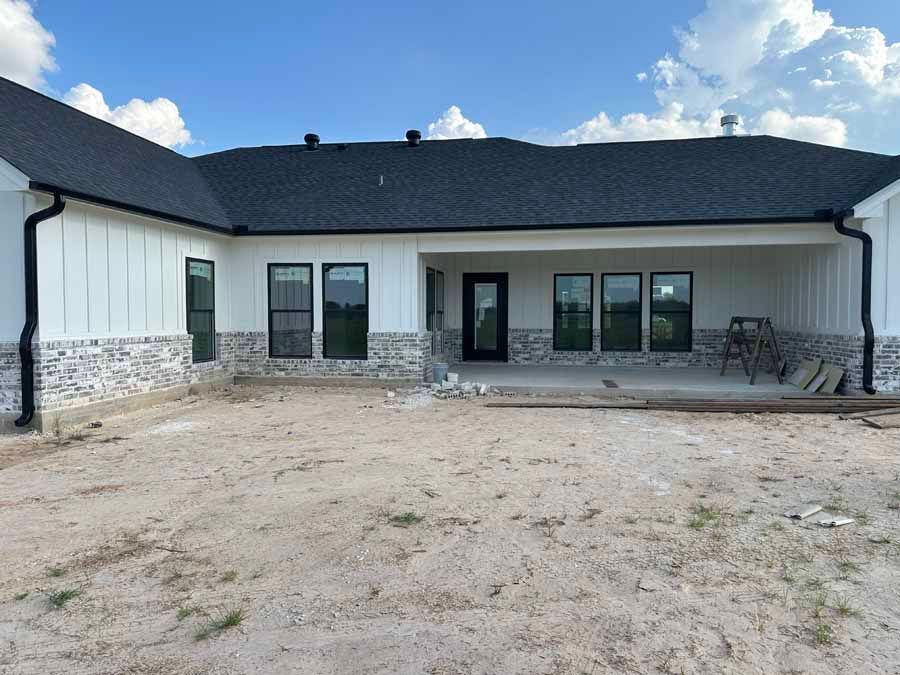 The back of a white house with a black roof is being built.