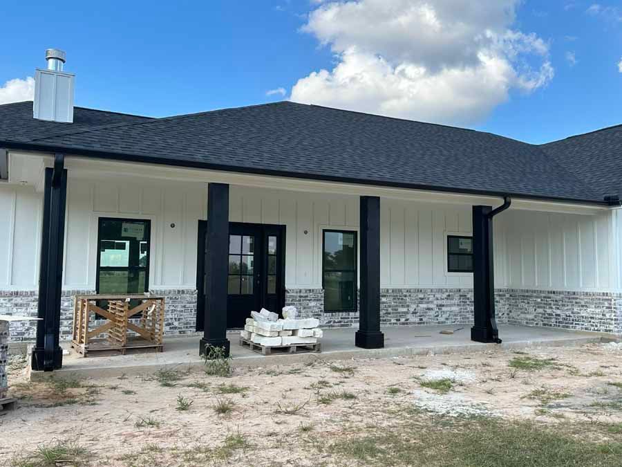 A white house with a black roof and a porch.