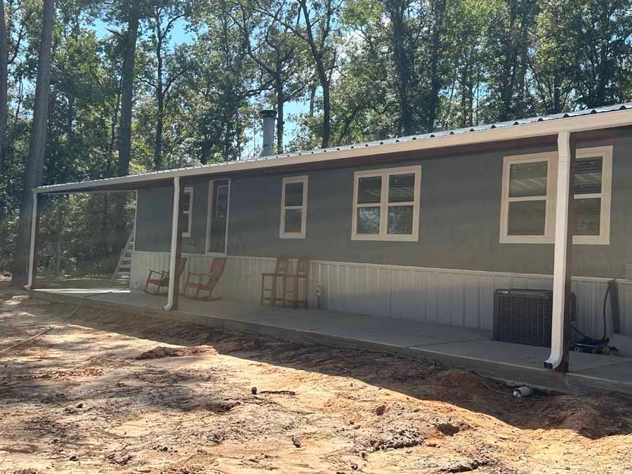A mobile home with a porch and chairs in front of it