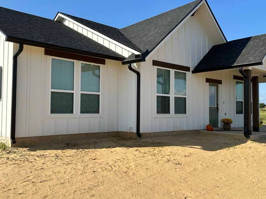 A white house with a black roof and a lot of windows