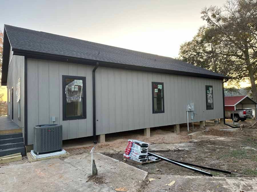 A large gray house with a black roof is being built.