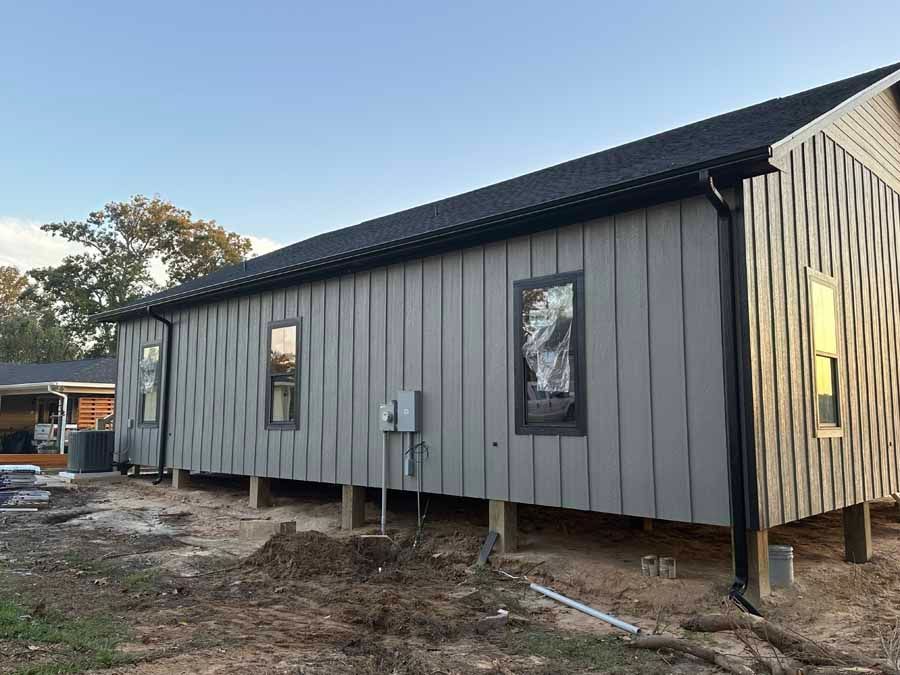 A house is being built on stilts in a dirt field.