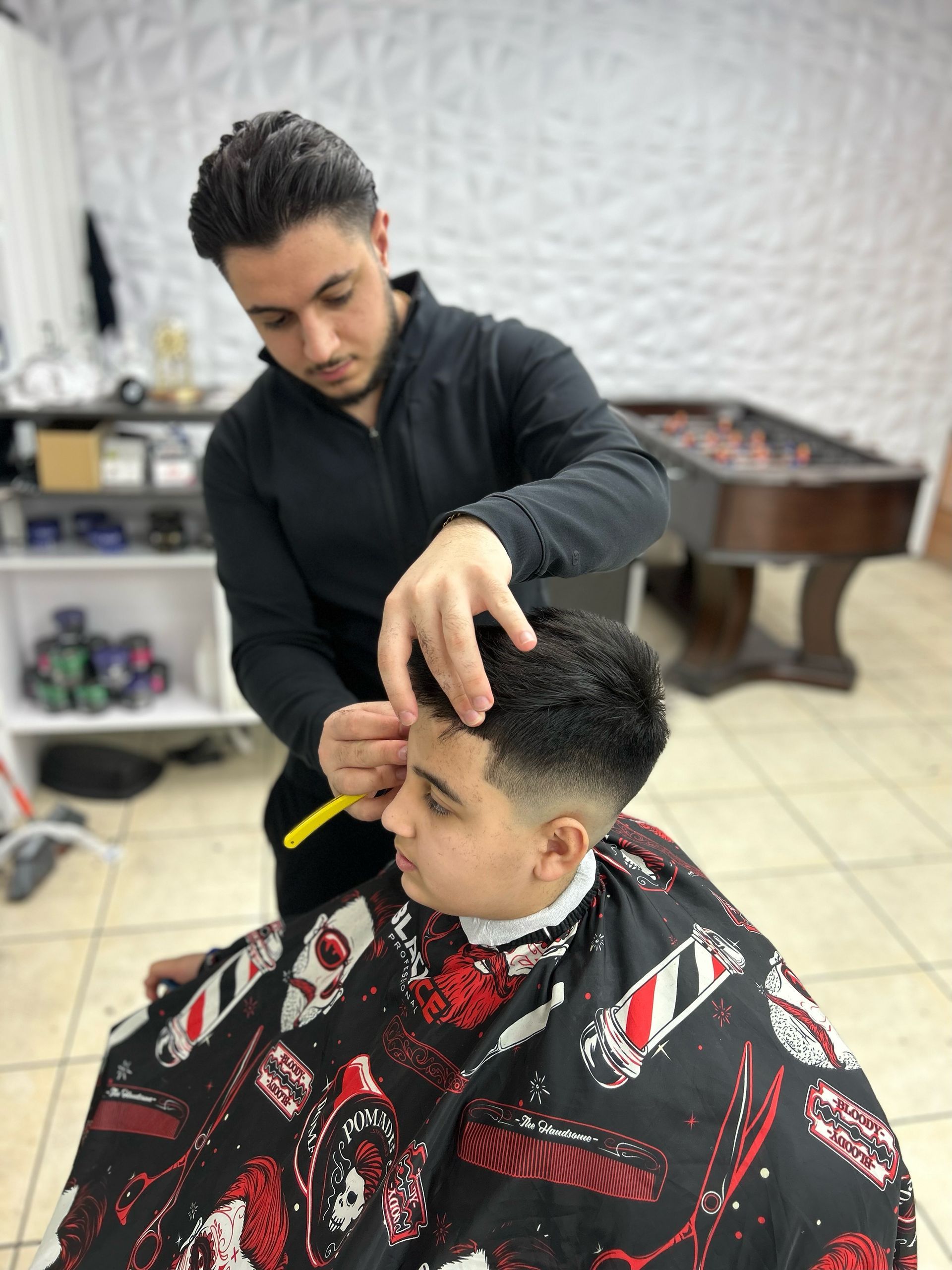 a barber is cutting a young boy 's hair in a barber shop