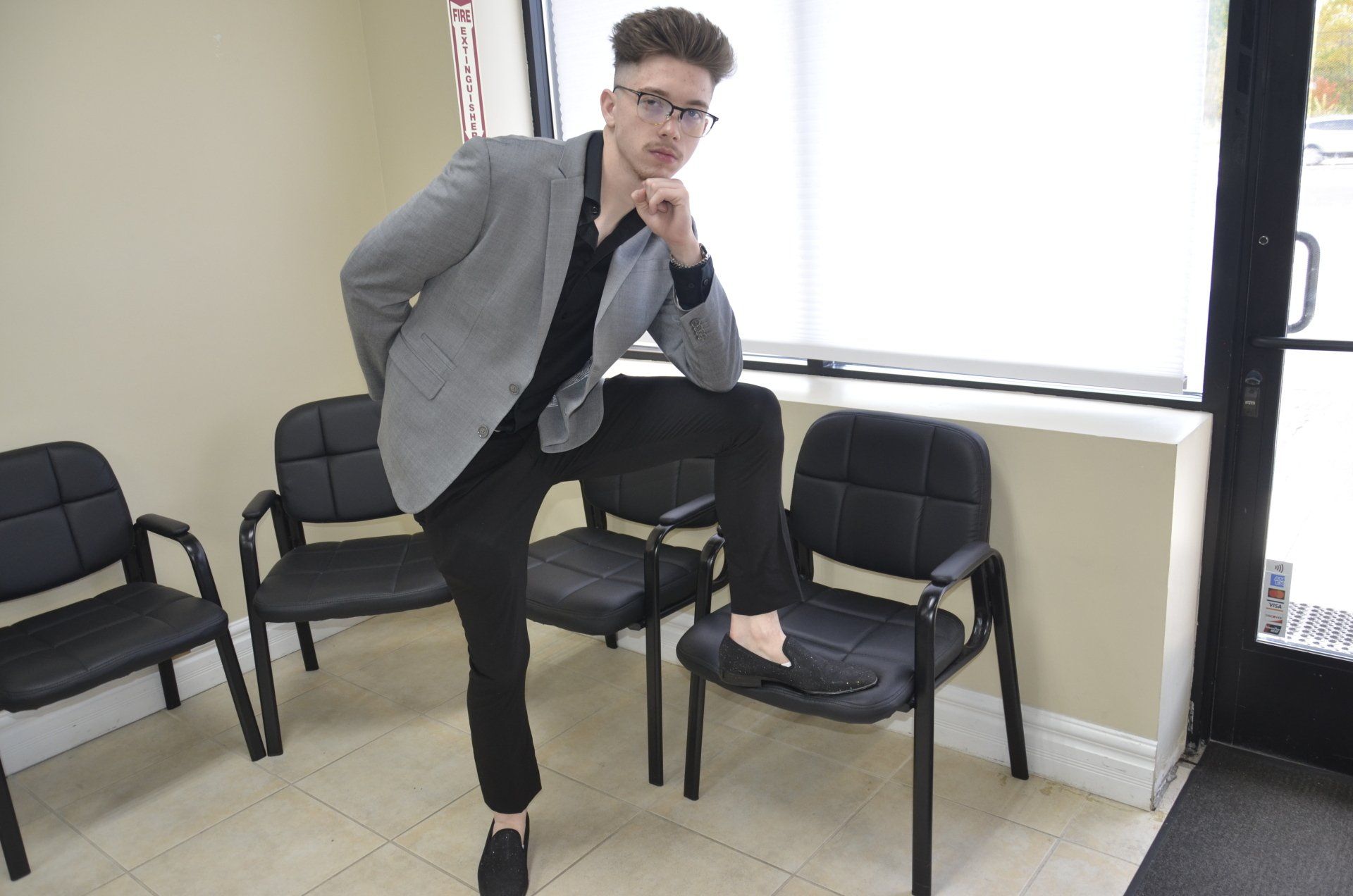 a man in a suit is standing on one leg in a waiting room .