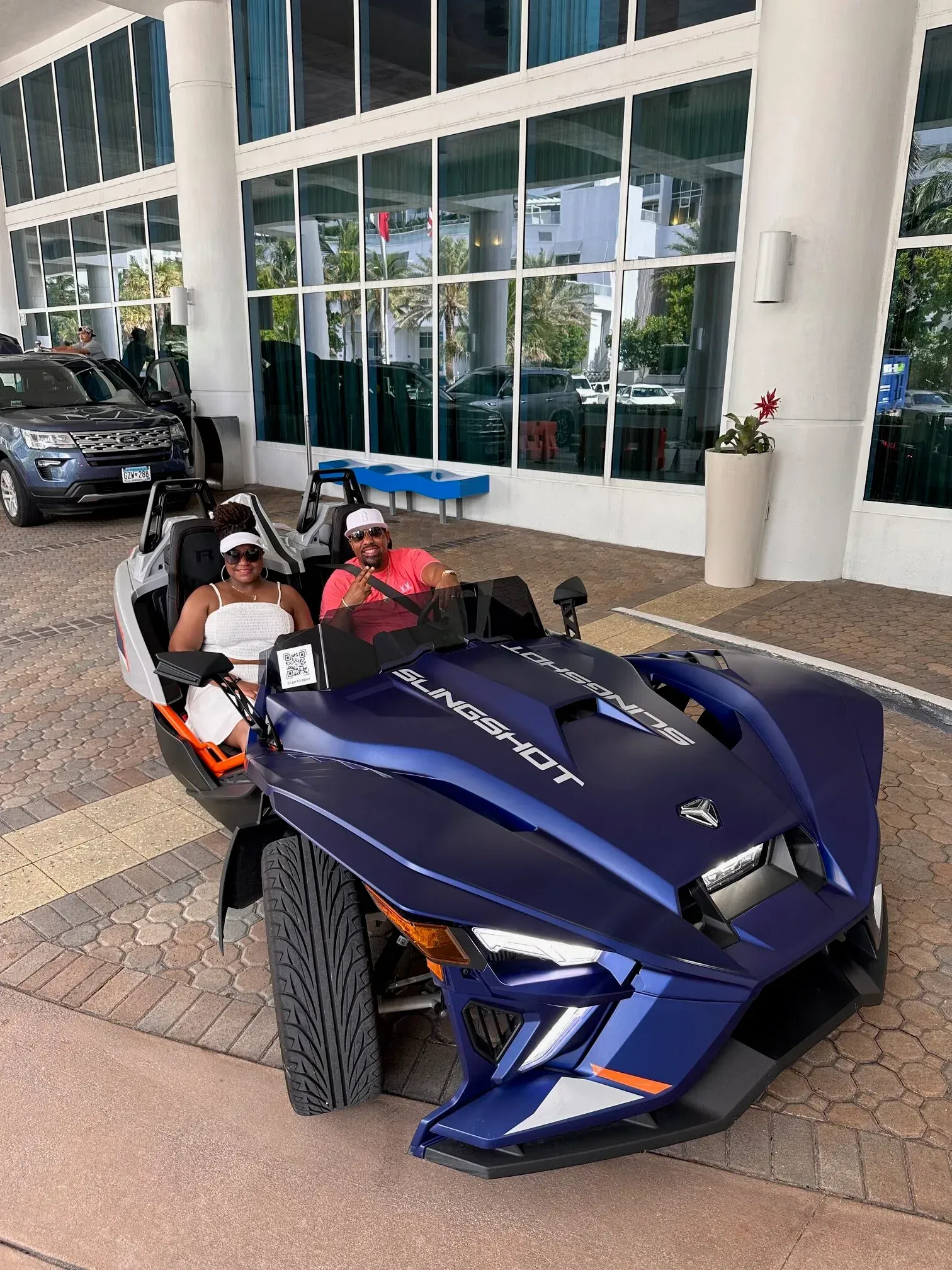 A couple is riding a slingshot in front of a building.