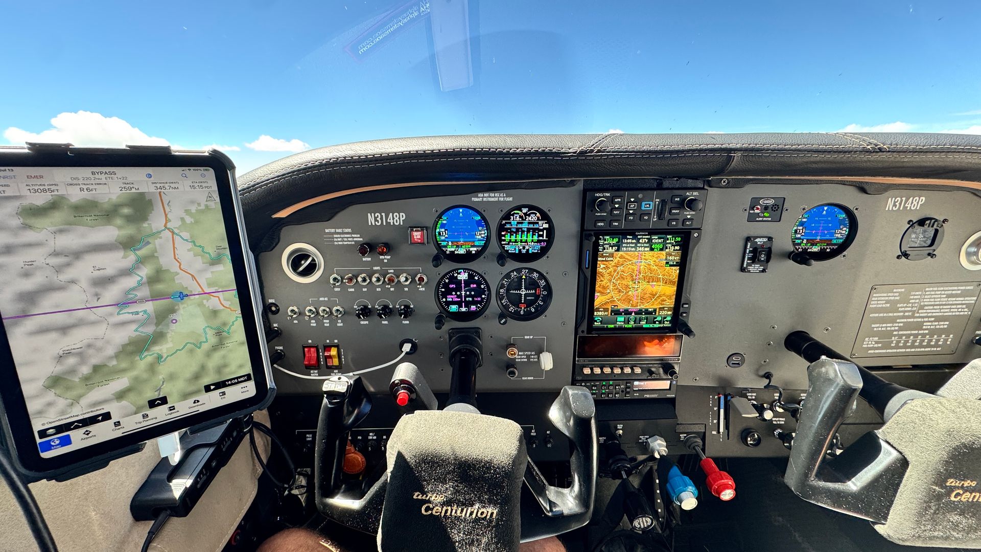 Cockpit view of a yellow and black airplane with control panels, gauges, and a windshield on a paved airstrip.