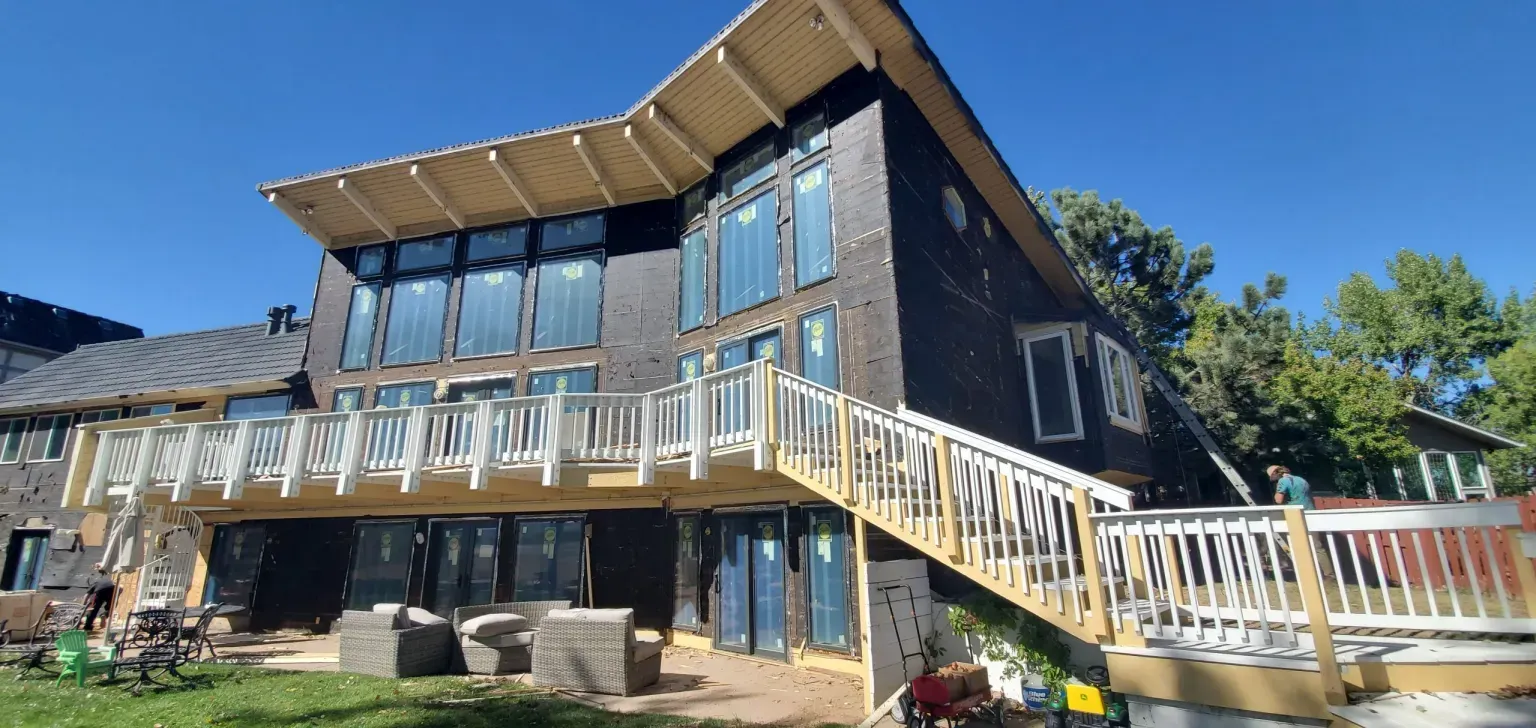 A large house with a deck and stairs is being built.
