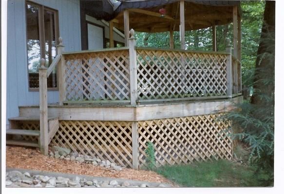 A wooden deck with a lattice railing and stairs
