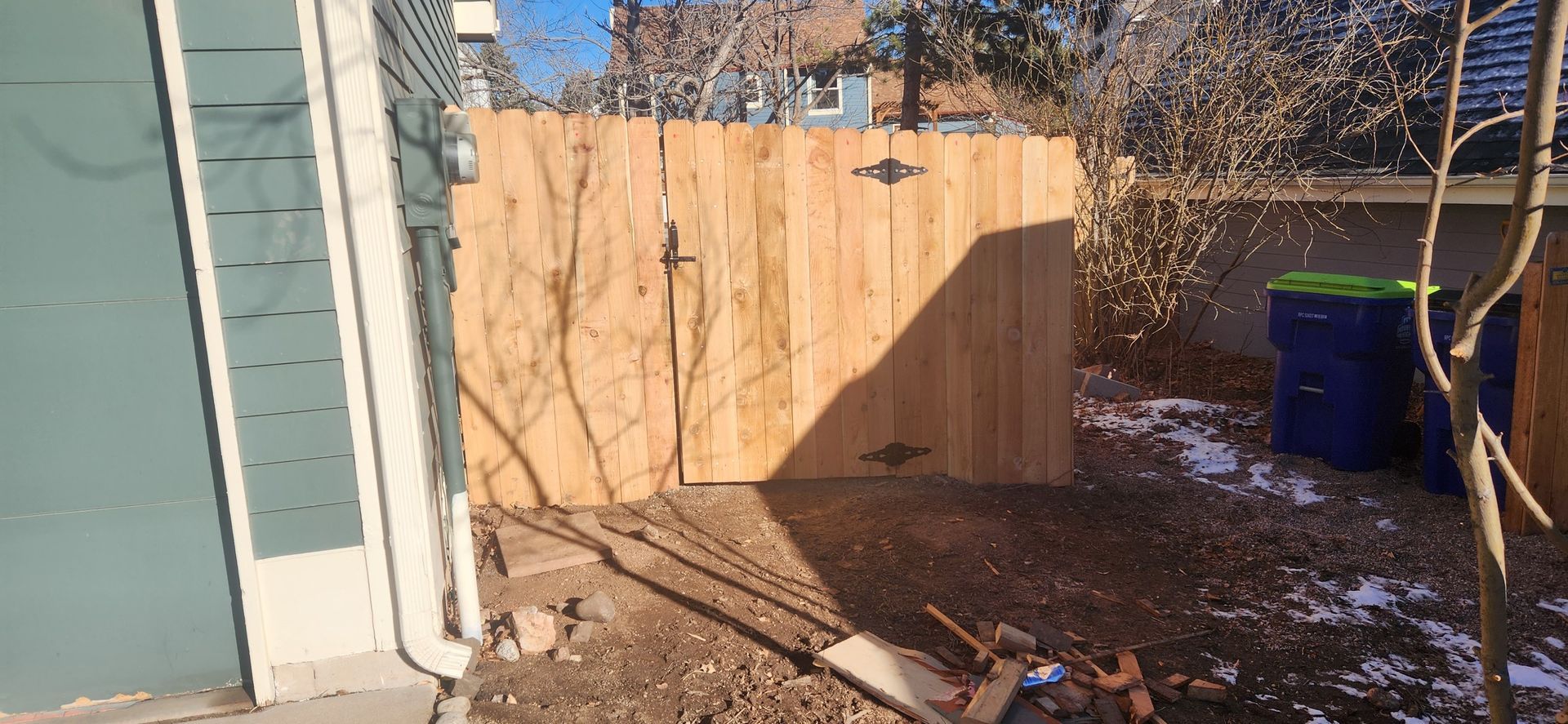 A wooden fence is being built in the backyard of a house.