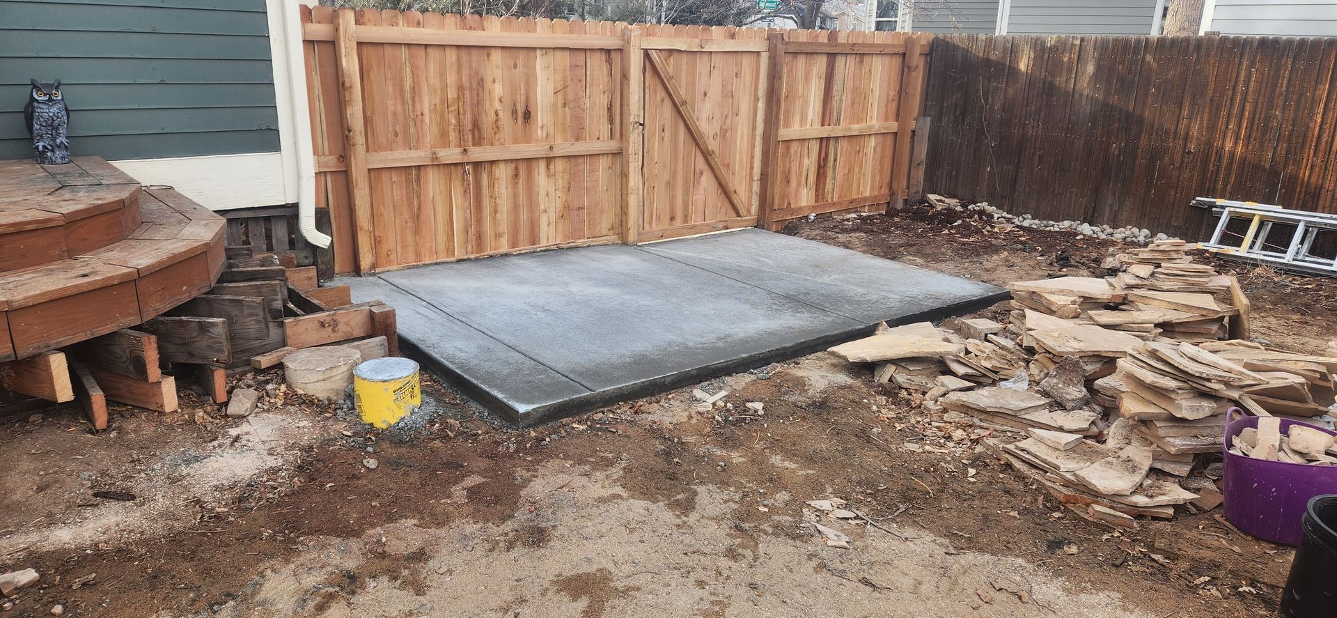 A shed is being built in a backyard next to a wooden fence.
