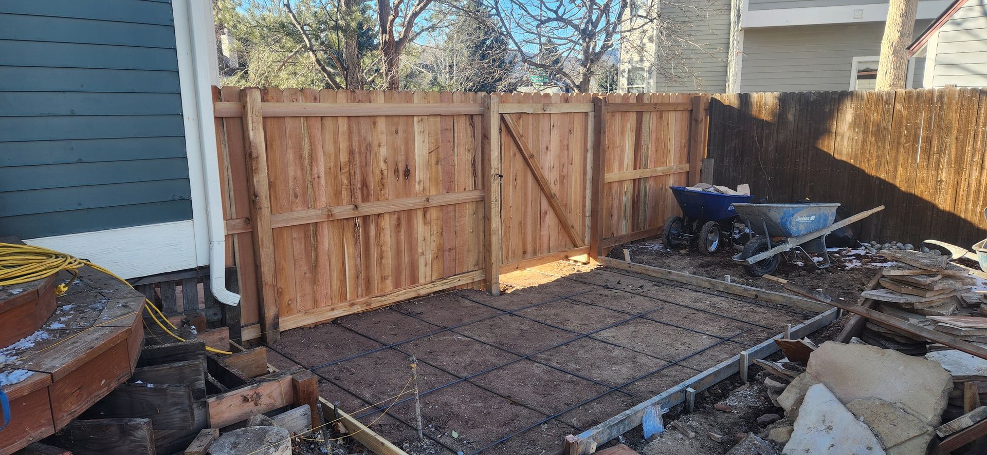 A wooden fence is being built in the backyard of a house.