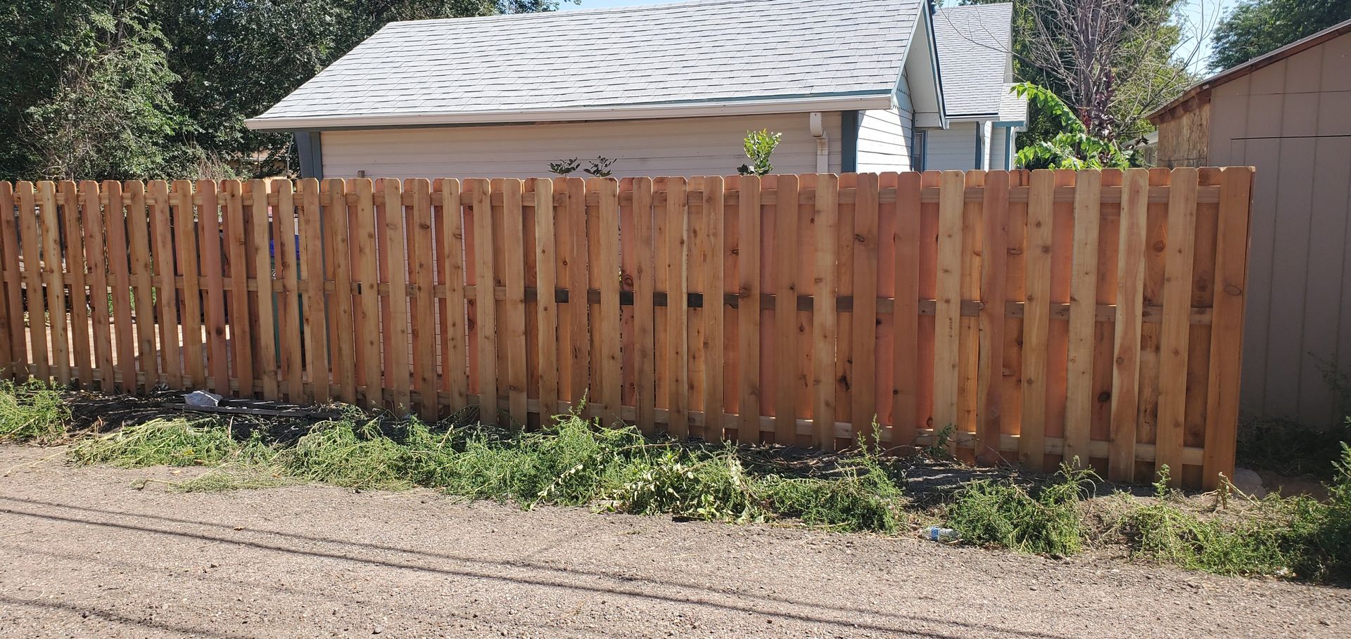 A wooden fence is in front of a house.