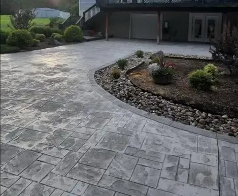 A concrete driveway leading to a house with a deck.