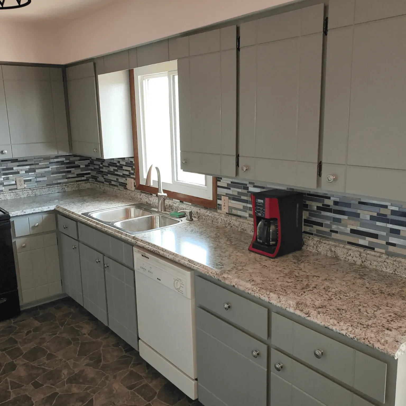 A kitchen with gray cabinets and granite counter tops